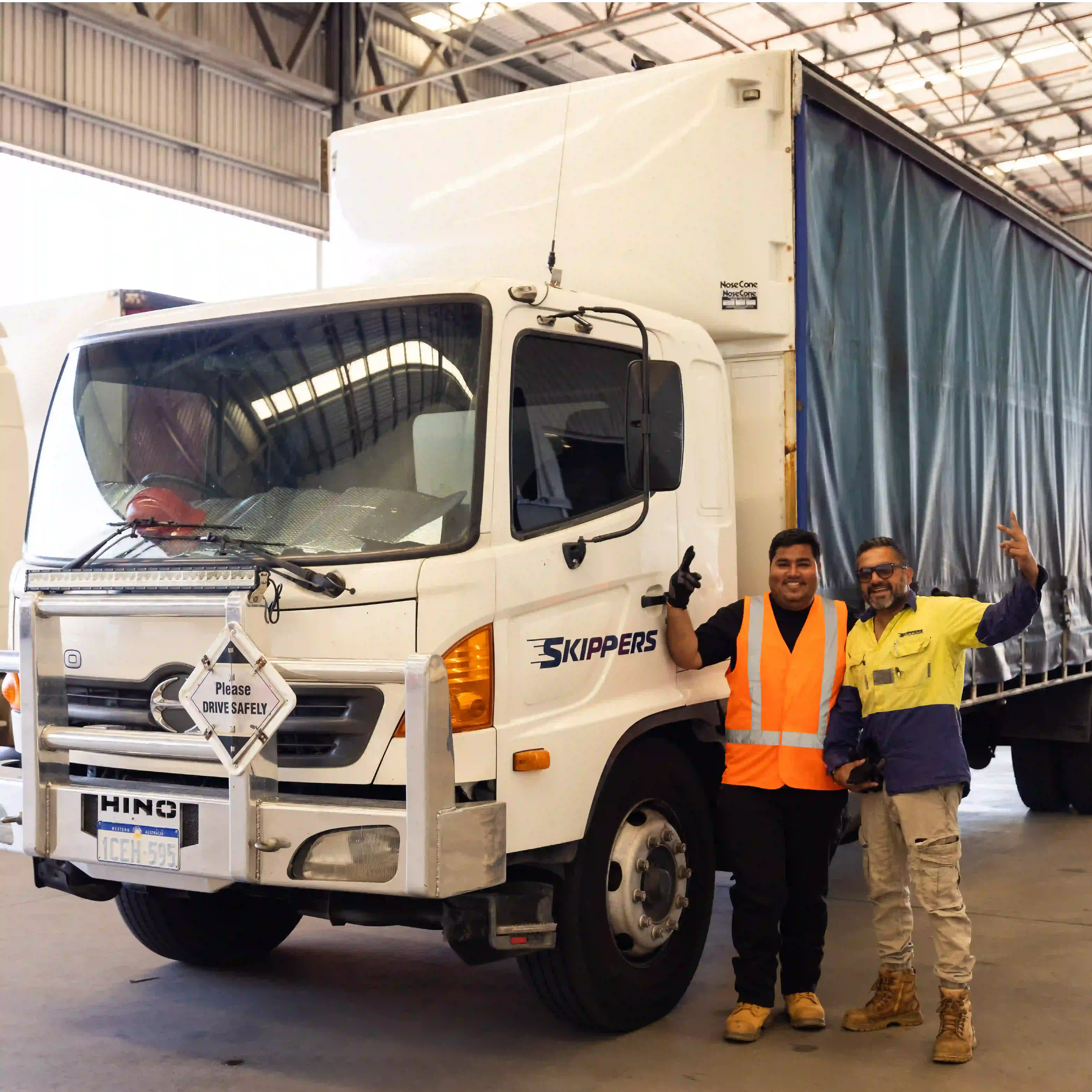 a picture of two happy guys with hands in the air standing next to a taxi truck that is being loaded