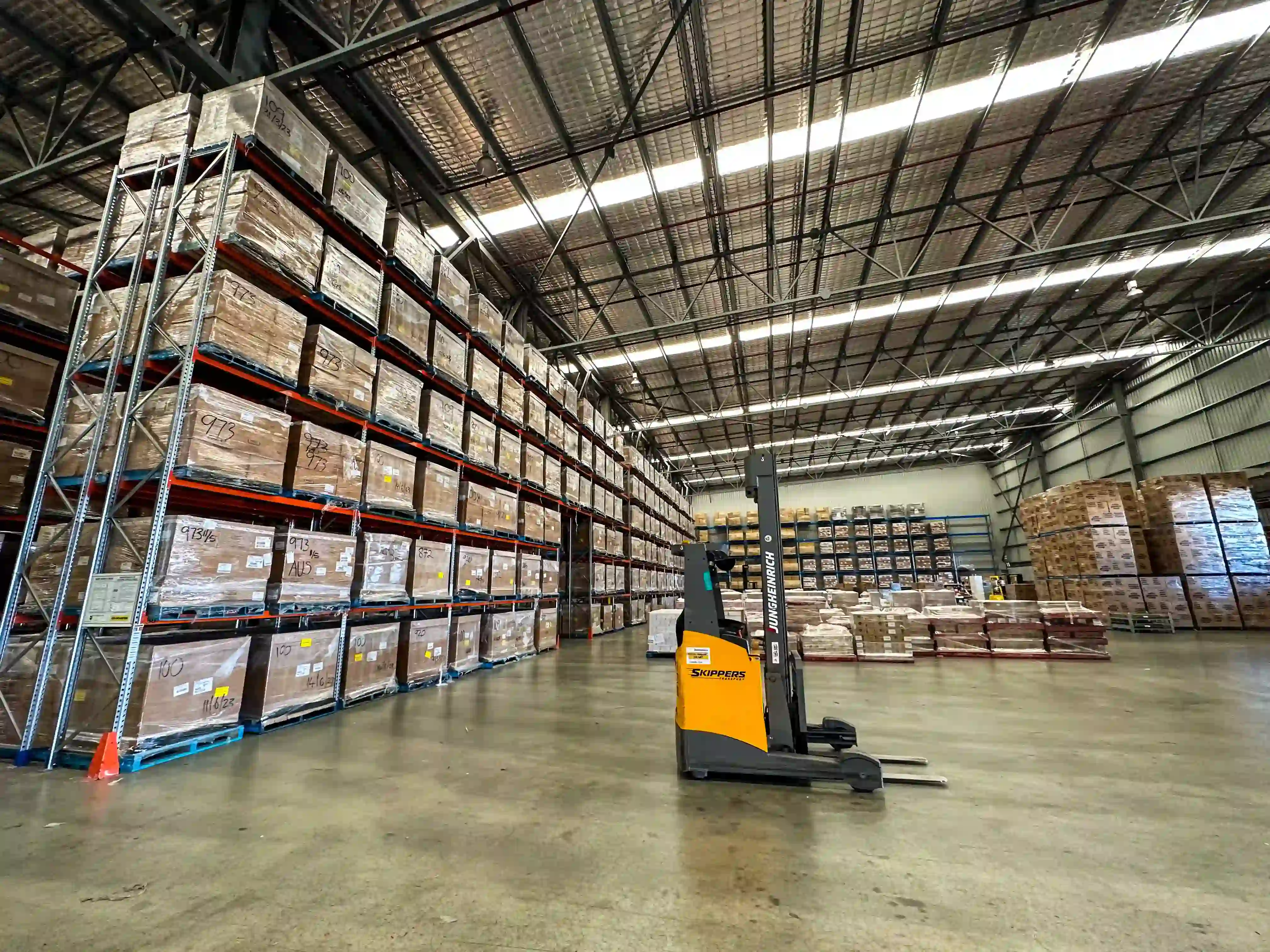 Skippers Transport warehouse with rows of stacked pallets and a forklift in Perth, Western Australia.